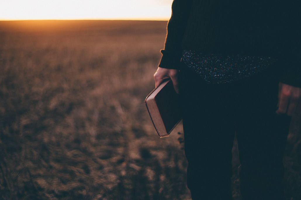 Believer holding a Bible at sunset